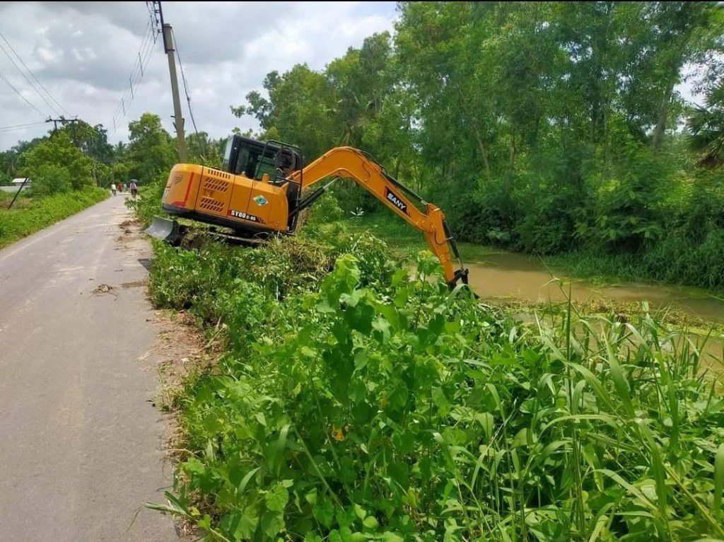 Excavator clearing a roadside channel